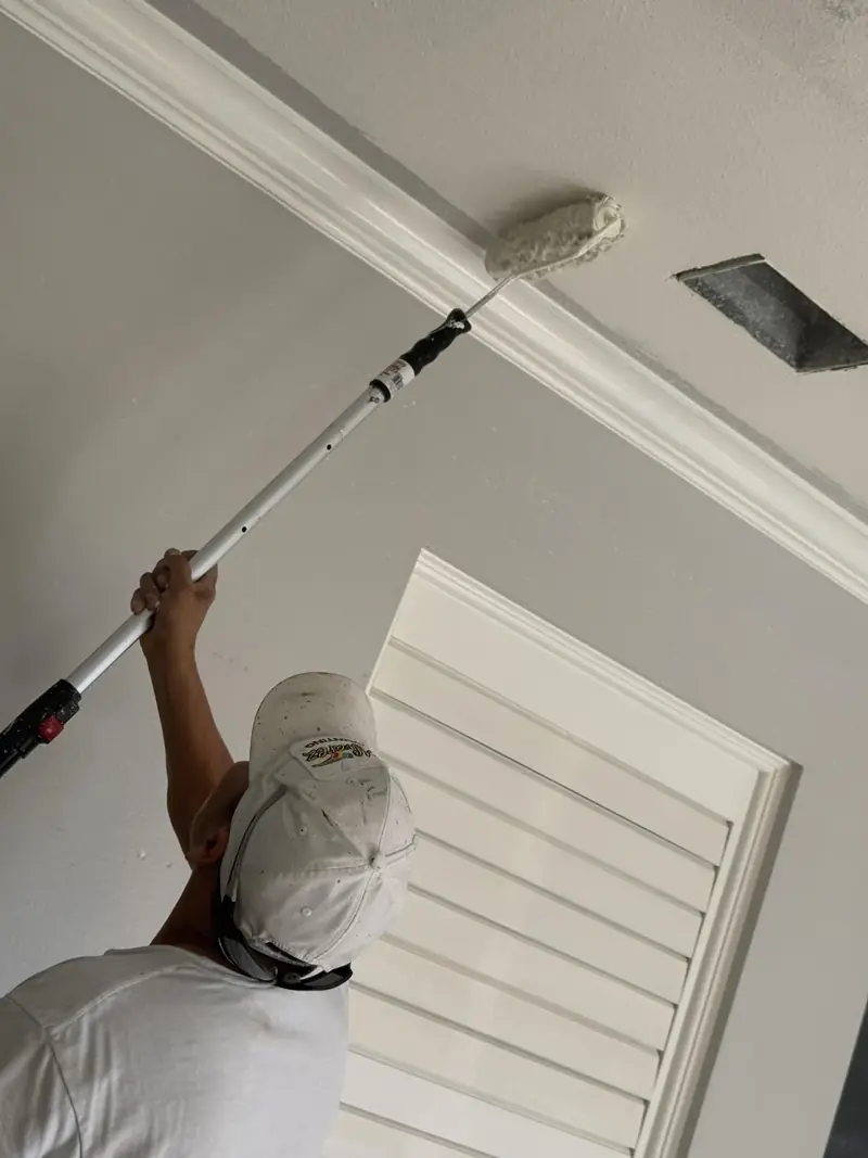 Alvarez Painting crew member painting an interior wall beside white cabinets