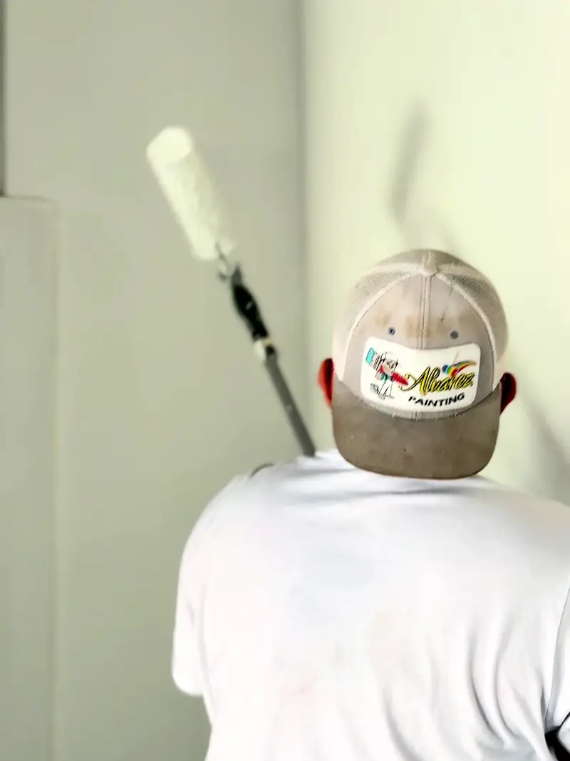 Alvarez Painting painter in a branded cap rolling paint on an interior wall