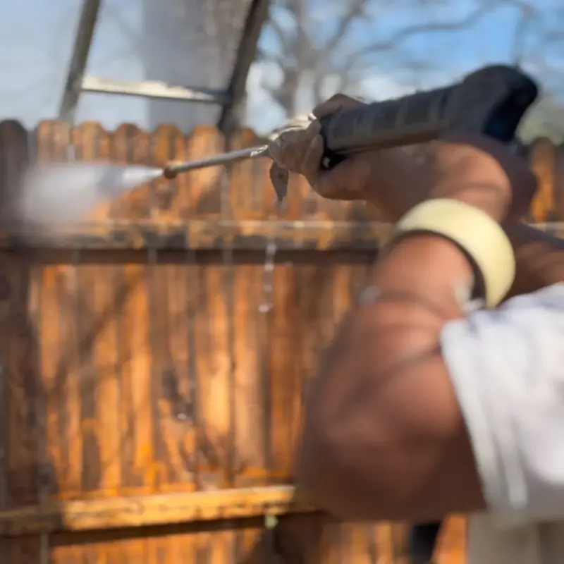 Alvarez Painting worker pressure washing a wood fence before staining